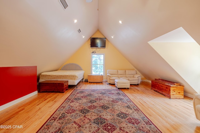 bedroom with baseboards, visible vents, wood finished floors, and lofted ceiling