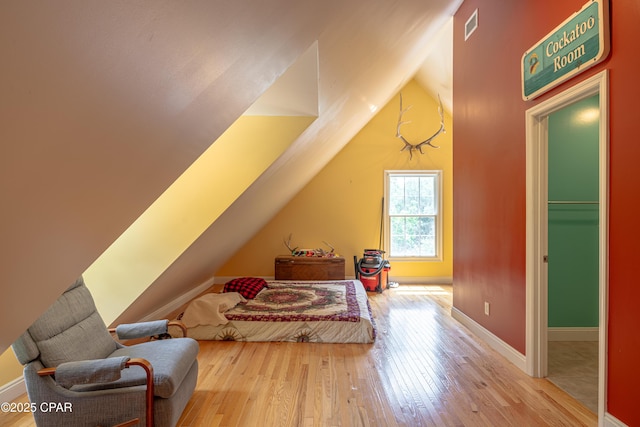 bedroom featuring baseboards, vaulted ceiling, visible vents, and hardwood / wood-style floors