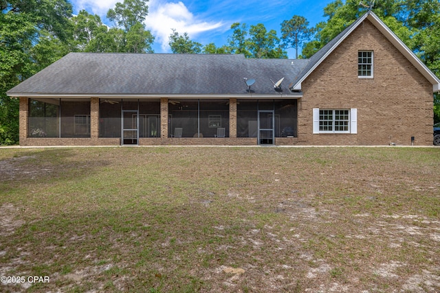 view of front of house with brick siding, a front yard, and a sunroom