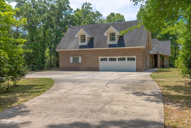 cape cod home with concrete driveway, brick siding, and an attached garage