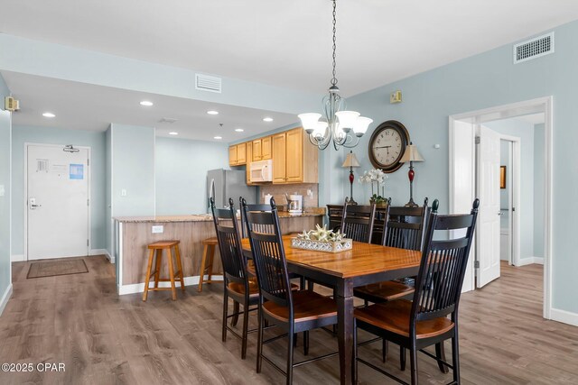 17739 Front Beach Rd Unit 1207W, Panama City Beach, FL 32413 - dining area with visible vents, wood finished floors, baseboards, and a notable chandelier