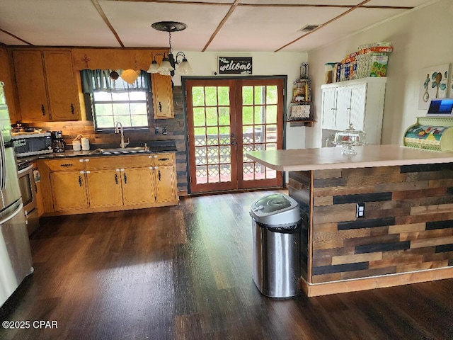kitchen featuring a sink, brown cabinetry, dark wood finished floors, and a notable chandelier