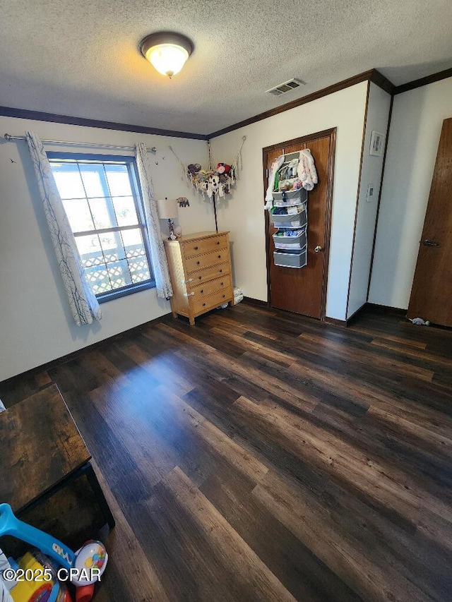 unfurnished bedroom with crown molding, a textured ceiling, wood finished floors, and visible vents