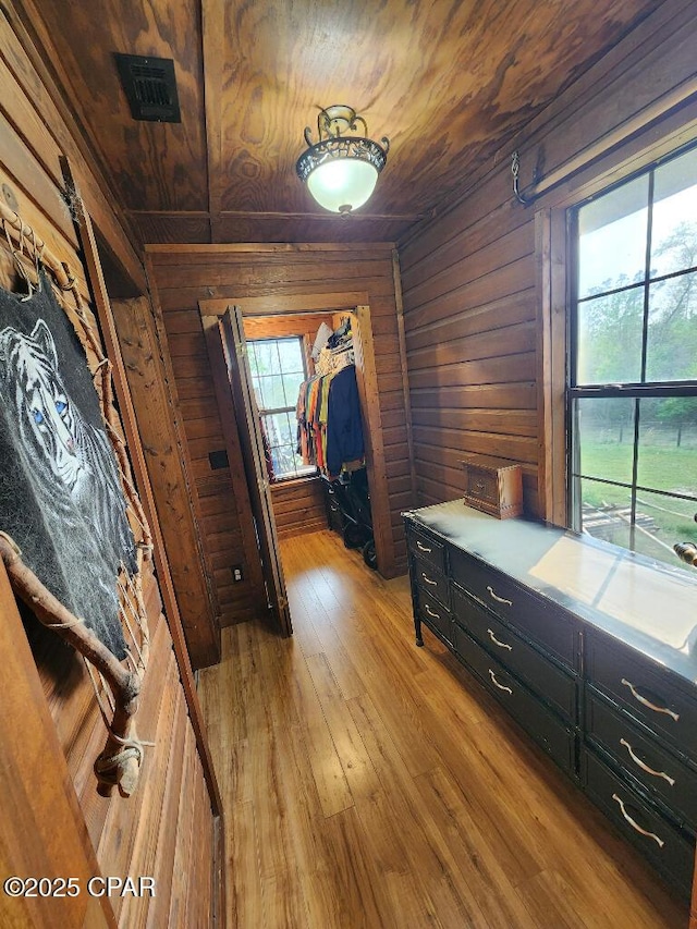 interior space featuring wooden walls, visible vents, wooden ceiling, and light wood finished floors