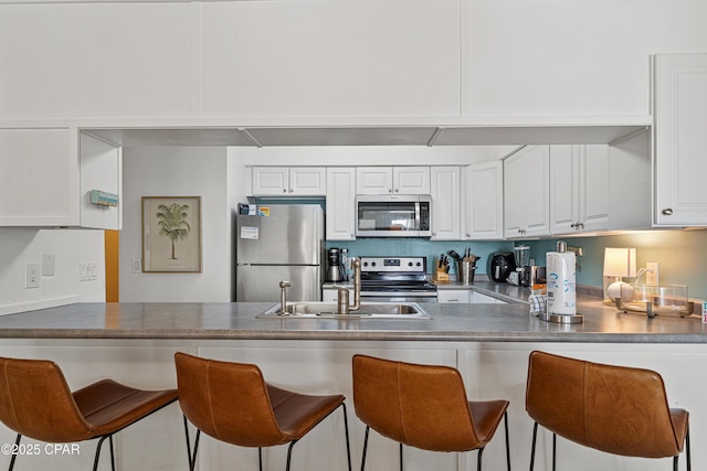 kitchen featuring stainless steel appliances, a peninsula, and white cabinetry