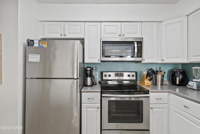 kitchen with stainless steel appliances, white cabinets, and light countertops