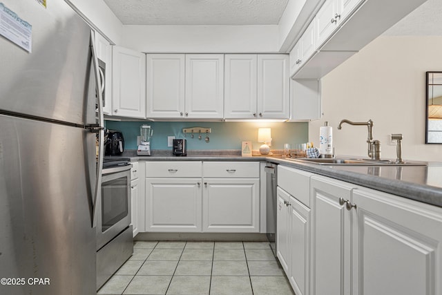kitchen with stainless steel appliances, white cabinetry, a sink, light tile patterned floors, and a textured ceiling
