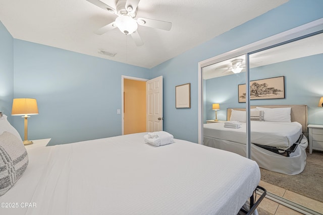 carpeted bedroom featuring tile patterned floors, a closet, and ceiling fan