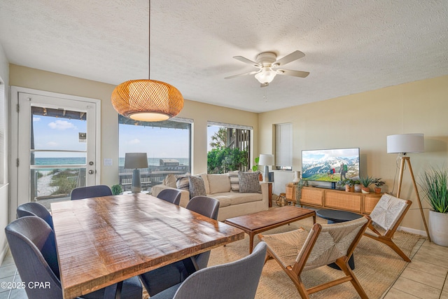 dining space featuring ceiling fan, a textured ceiling, light tile patterned floors, and baseboards