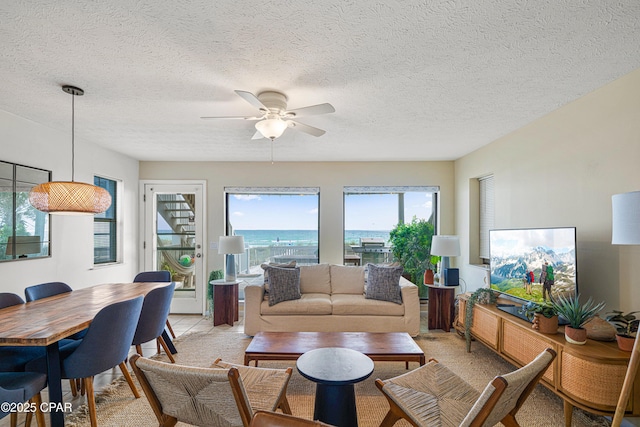 living room with healthy amount of natural light, ceiling fan, and a textured ceiling