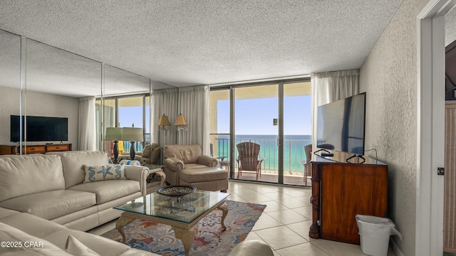 living room featuring a textured ceiling, floor to ceiling windows, a textured wall, and light tile patterned flooring