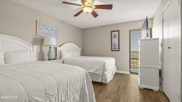 bedroom featuring wood finished floors, a textured ceiling, baseboards, and a ceiling fan