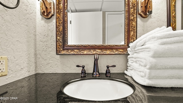 bathroom with a sink, a drop ceiling, and a textured wall