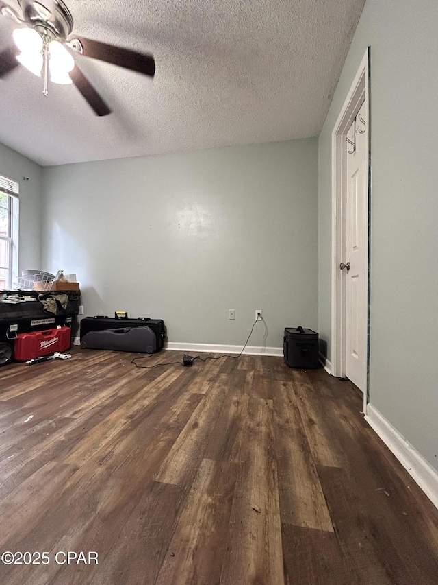 interior space featuring a textured ceiling, ceiling fan, and dark wood-type flooring