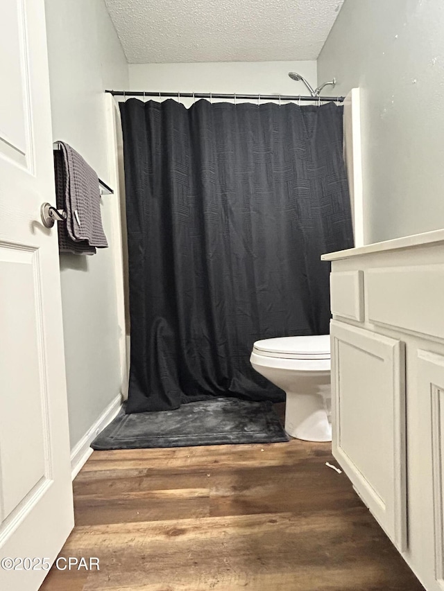 full bathroom featuring a textured ceiling, wood finished floors, toilet, and a shower with curtain
