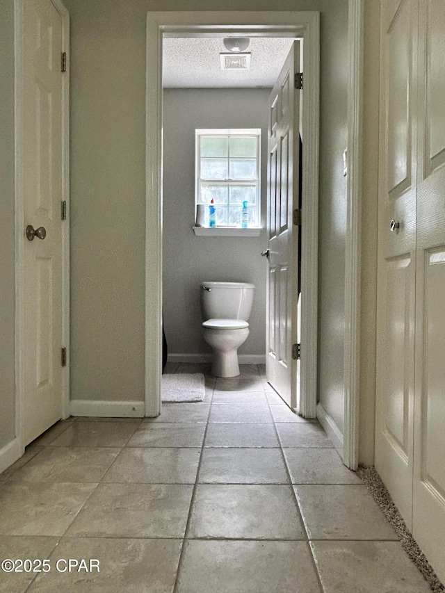 bathroom featuring baseboards, tile patterned flooring, and toilet