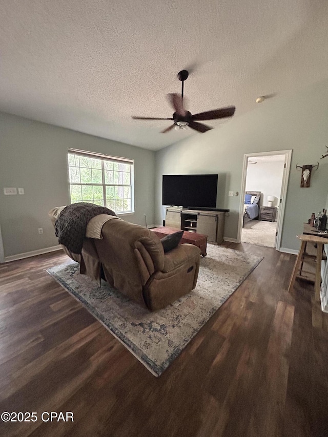 living area with baseboards, a ceiling fan, dark wood-style floors, and a textured ceiling