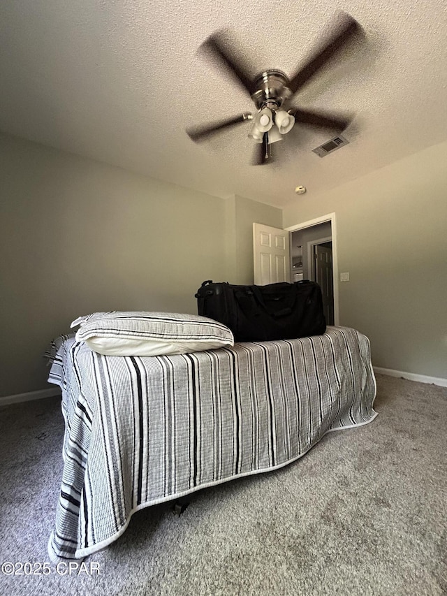 carpeted bedroom featuring a textured ceiling, visible vents, and baseboards