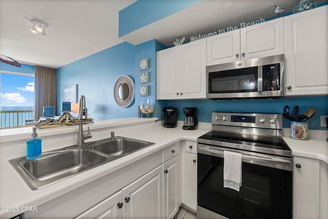 kitchen with a sink, stainless steel appliances, tile patterned floors, light countertops, and white cabinets