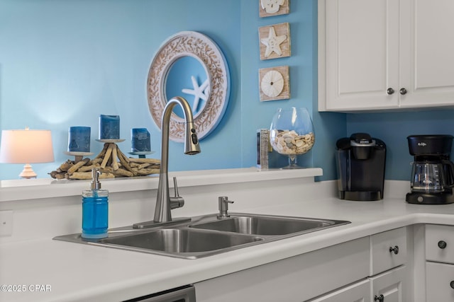 kitchen with light countertops, white cabinets, and a sink