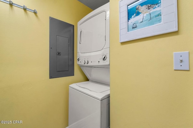 laundry room with stacked washing maching and dryer, laundry area, and electric panel