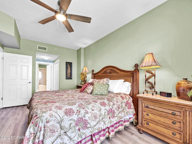 bedroom featuring ceiling fan, light wood-style flooring, ensuite bathroom, and visible vents