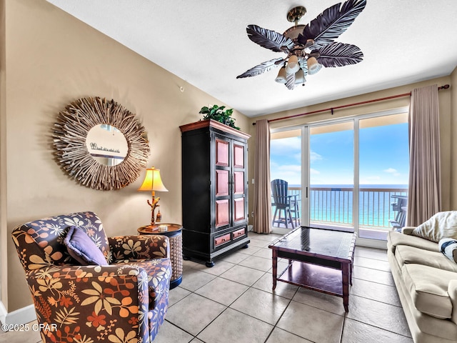 living area featuring a water view, light tile patterned floors, and ceiling fan
