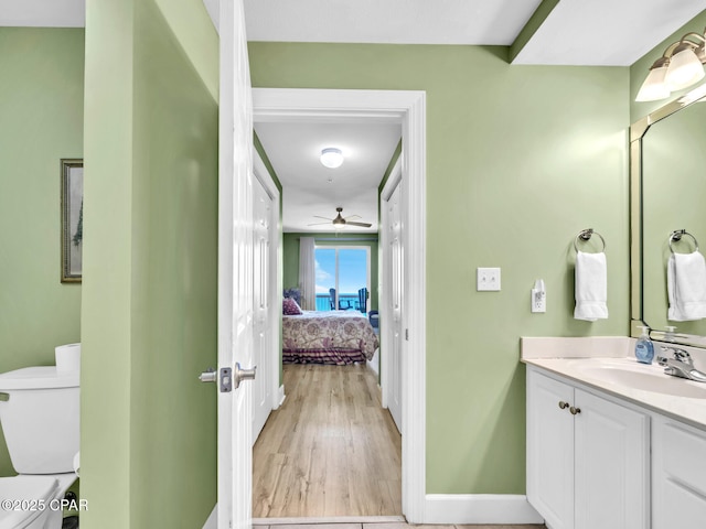 ensuite bathroom featuring connected bathroom, toilet, wood finished floors, ceiling fan, and vanity