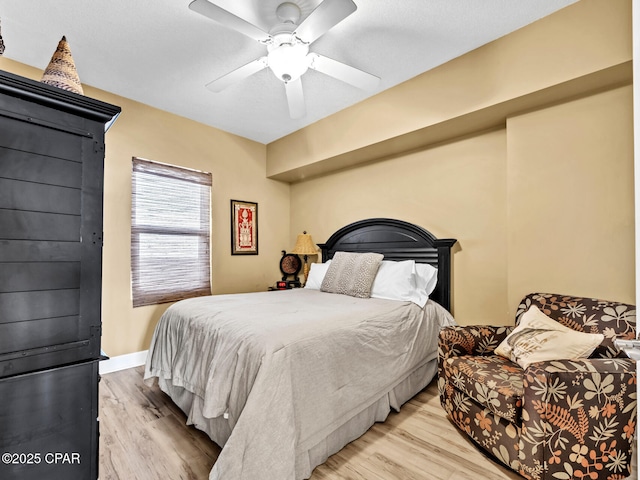 bedroom with light wood finished floors, baseboards, and a ceiling fan
