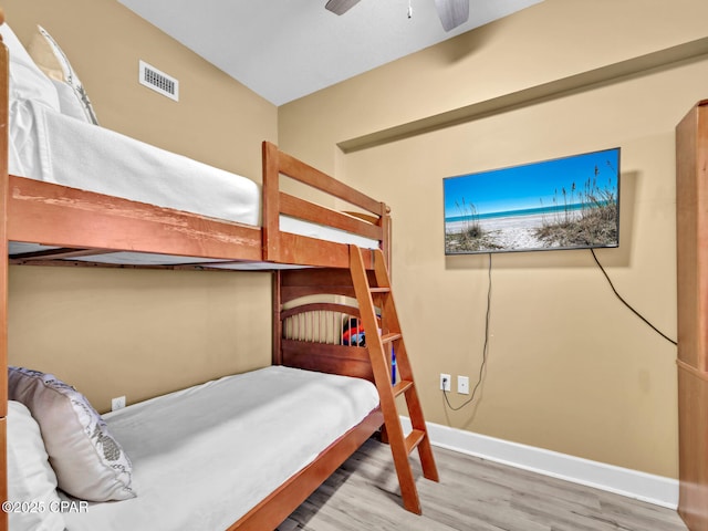 bedroom with baseboards, ceiling fan, visible vents, and wood finished floors
