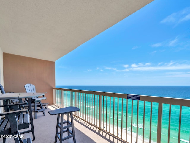 balcony featuring a view of the beach and a water view