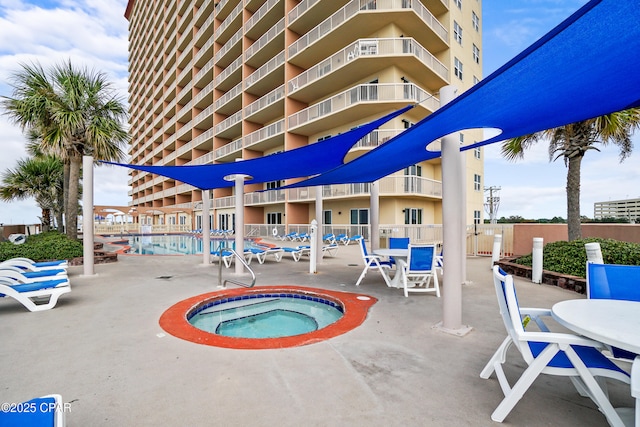 pool with fence, a community hot tub, and a patio area