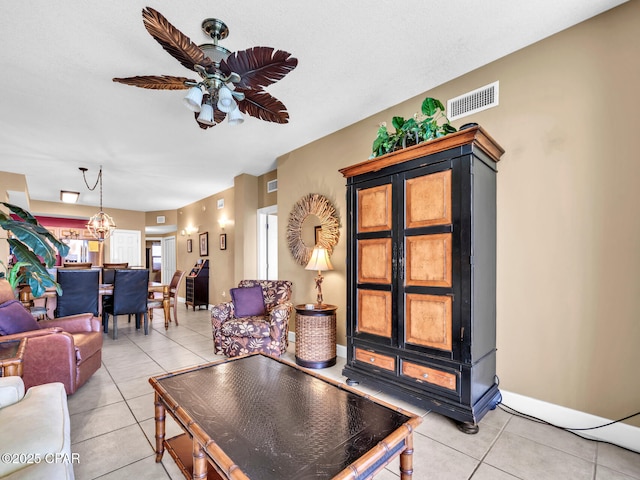 living area with light tile patterned floors, visible vents, and ceiling fan