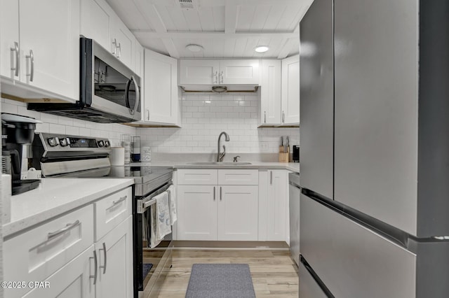 kitchen with stainless steel appliances, a sink, light wood finished floors, backsplash, and white cabinets