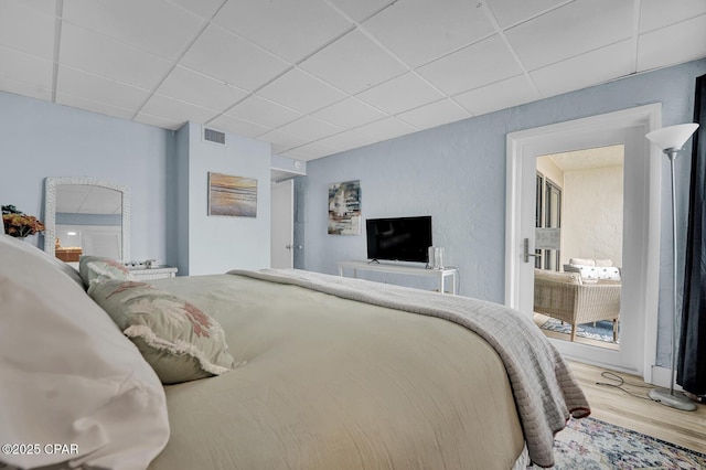 bedroom featuring a drop ceiling and wood finished floors