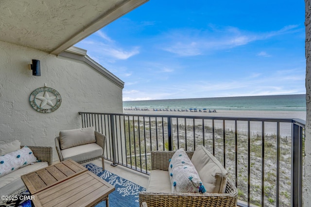 balcony with view of water and beach and an outdoor living space