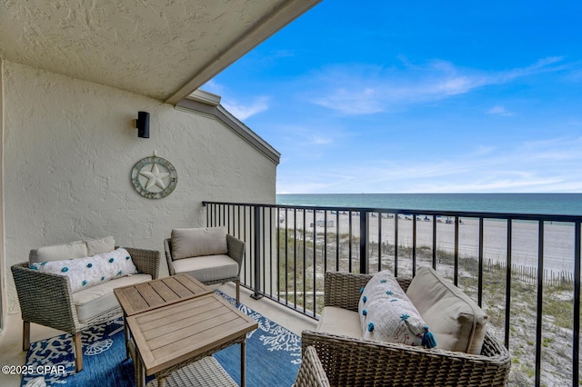 balcony with view of water and beach and an outdoor living space