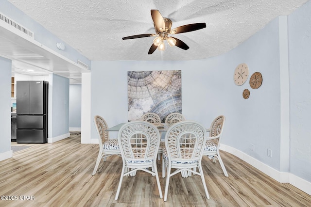 dining room with a ceiling fan, baseboards, wood finished floors, and a textured ceiling