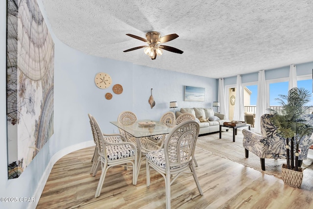 dining space with light wood-style floors, ceiling fan, and a textured ceiling