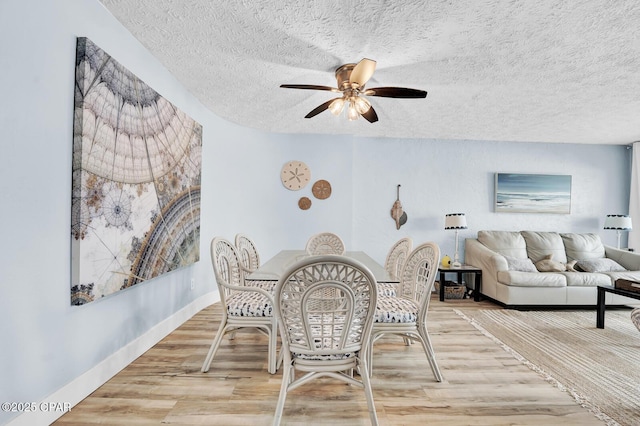 dining area with a textured ceiling, ceiling fan, and light wood-style floors