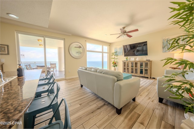 living area with light wood-type flooring, baseboards, and ceiling fan