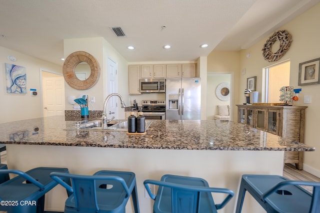 kitchen with a sink, a peninsula, visible vents, recessed lighting, and appliances with stainless steel finishes