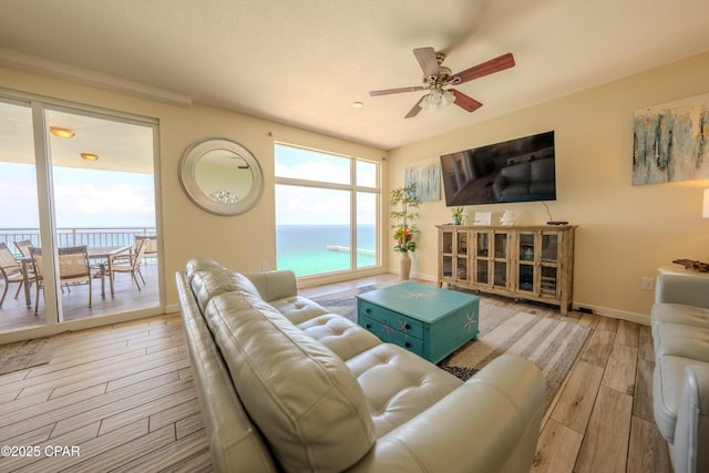 living room featuring wood finished floors, baseboards, and ceiling fan