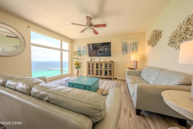 living area featuring wood finished floors, baseboards, and ceiling fan