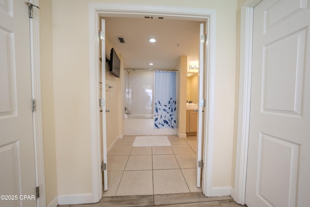 corridor featuring recessed lighting, baseboards, light tile patterned floors, and visible vents
