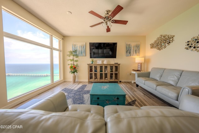 living room with ceiling fan, baseboards, and wood finished floors