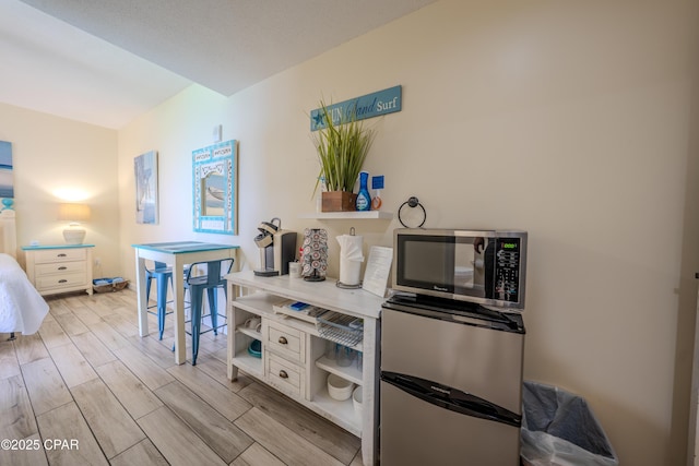 kitchen with open shelves, light wood-style floors, stainless steel microwave, and white cabinetry