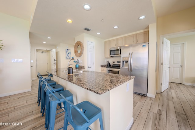 kitchen with stone countertops, baseboards, a sink, wood finish floors, and appliances with stainless steel finishes
