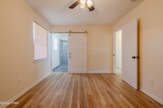 215 Tates Ln, Southport, FL 32409 - spare room with light wood finished floors, a barn door, baseboards, and a ceiling fan