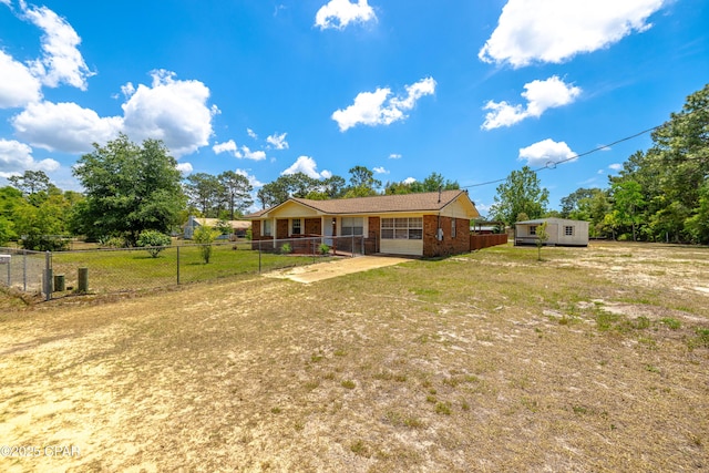 215 Tates Ln, Southport, FL 32409 - back of house featuring brick siding, driveway, fence, and a lawn